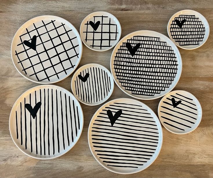 six plates with black and white designs on them sitting on a wooden table top next to each other