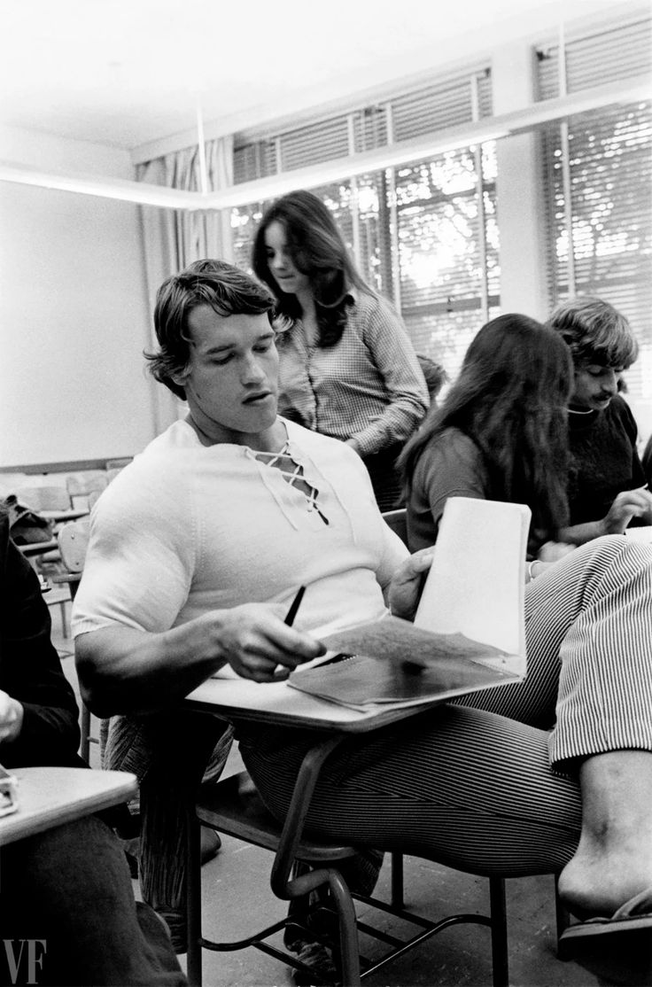 black and white photograph of students in classroom with one male writing on a notepad