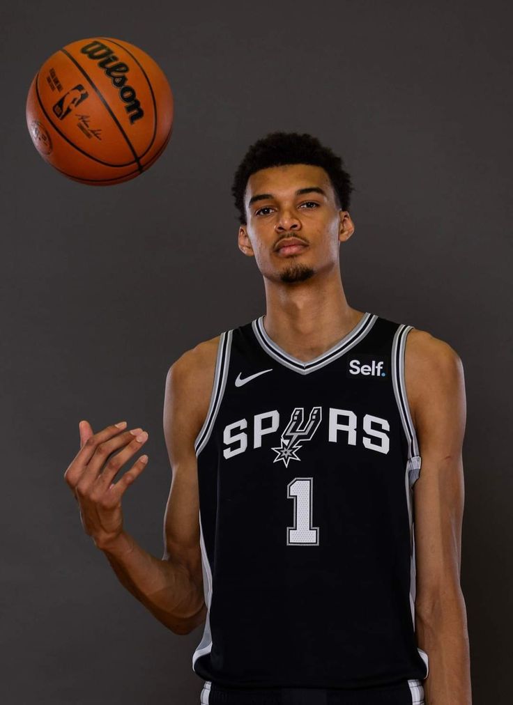 a young man holding a basketball in his right hand and looking up at the ball