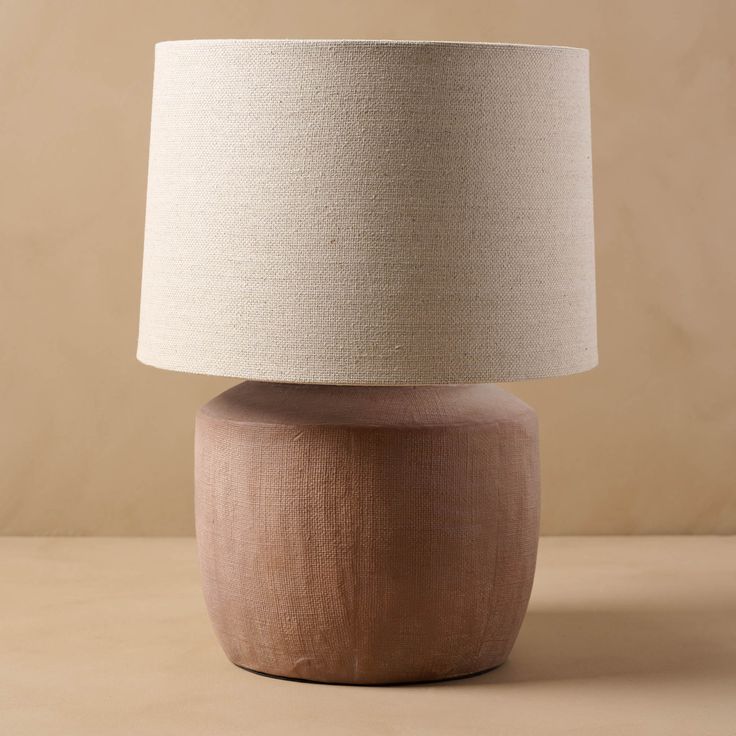 a lamp that is sitting on top of a wooden table next to a beige wall