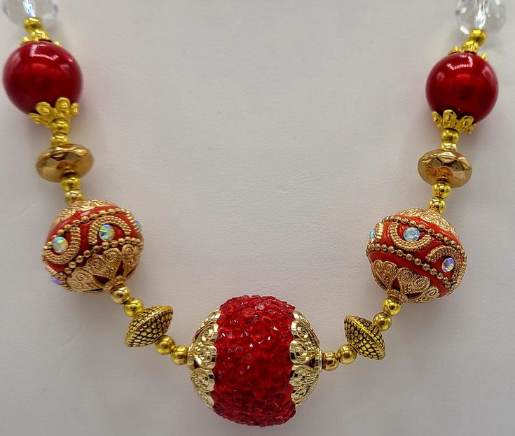 This 21 inch necklace is made with gold and red specialty beads, gold plated seed beads, gold spacer beads, gold crystal beads and clear crystal beads.  The closure on the necklace is a 14 K gold plated toggle clasp.  Earrings are made with the gold and red specialty beads and the gold plated seed beads.  The earrings hang a total of 1 3/4 inches long and are made with 14 K gold plated earring wires and a 14 K gold plated head pin. Gold Jewelry With Colorful Beads For Celebration, Gold Beaded Necklace For Festive Costume Jewelry, Festive Gold Necklace With Colorful Beads, Festive Gold Beaded Necklaces With Spacer Beads, Festive Gold Beaded Necklaces With Colorful Beads, Red Jewelry With Gold Beads For Jewelry Making, Gold Beaded Necklace With Faceted Beads For Celebration, Gold Beaded Necklace With Faceted Beads For Festive Occasions, Traditional Gold Jewelry For Christmas