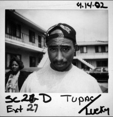 a black and white photo of a man wearing a hat with the words 32 d tupaca on it