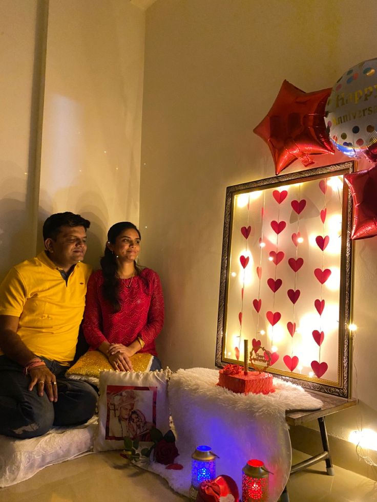 a man and woman sitting next to each other in front of a cake with candles on it