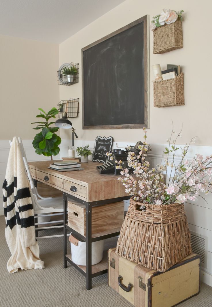 a wooden desk topped with lots of drawers next to a chalkboard and potted plants