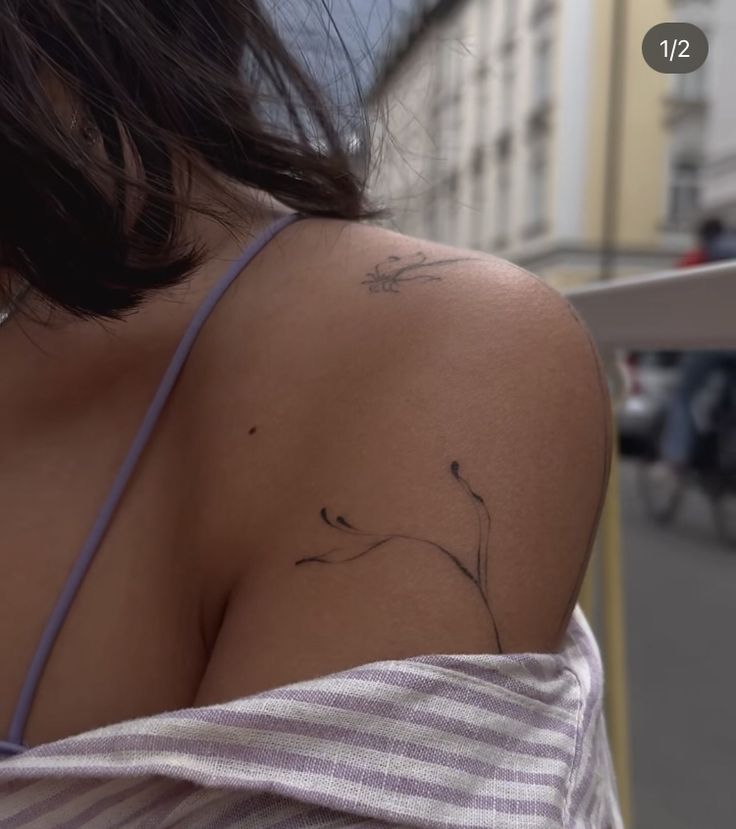 the back of a woman's shoulder with a bird tattoo on her left arm