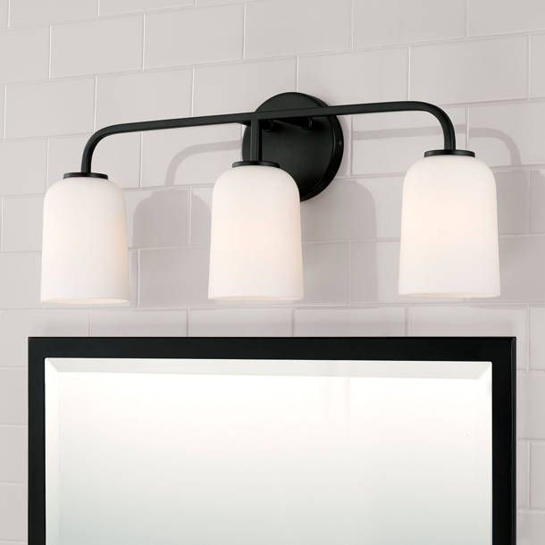 a bathroom vanity with three lights and a mirror on the wall next to it,