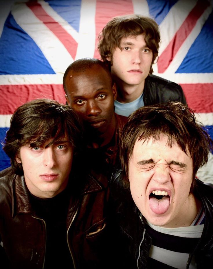 four young men with their mouths open in front of an union jack flag background,