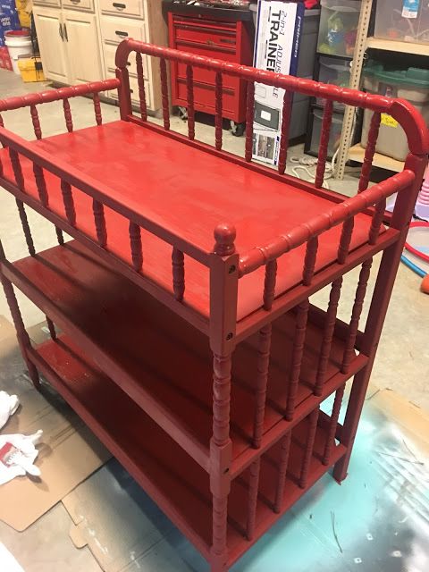 a red cart with three shelves on it in a room filled with other furniture and tools