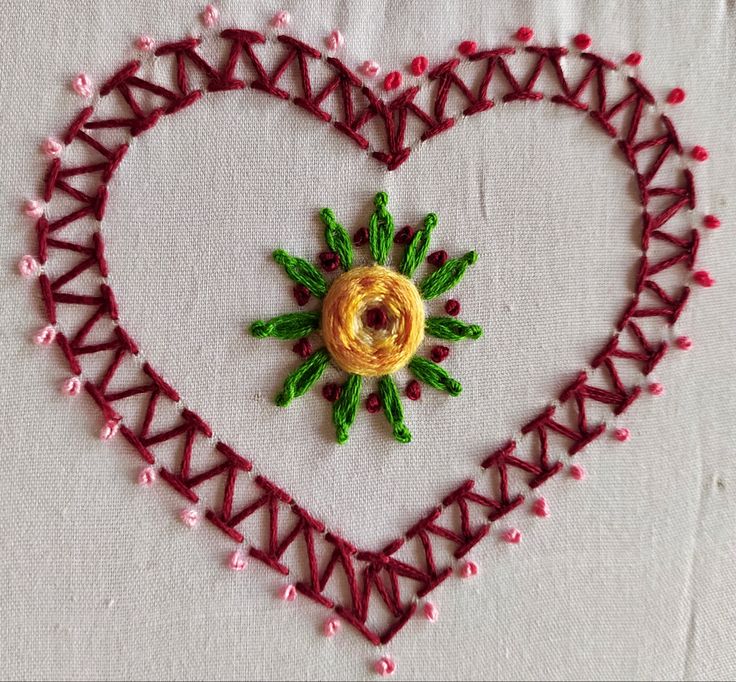 a heart - shaped embroidered piece with a flower in the center