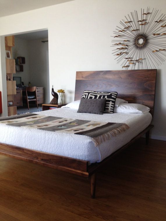 a large bed sitting on top of a wooden floor next to a wall mounted clock