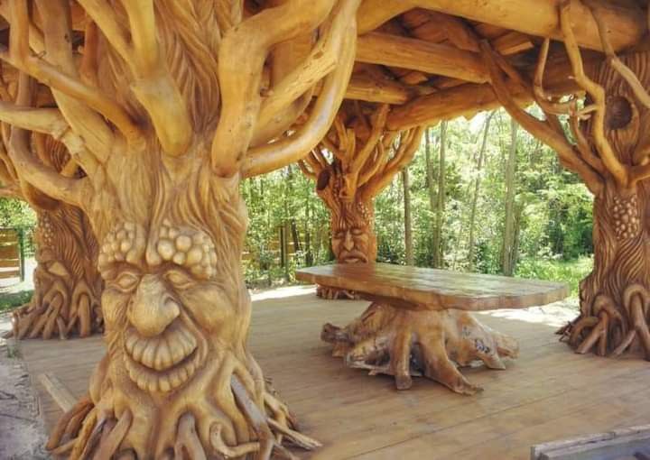 a wooden structure with carved trees and benches