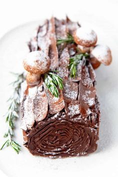 a piece of chocolate cake with powdered sugar and sprig of rosemary on top