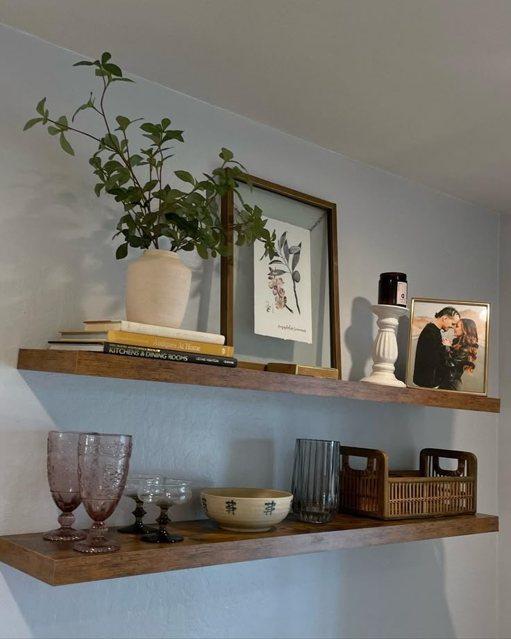 two wooden shelves with pictures and vases on them