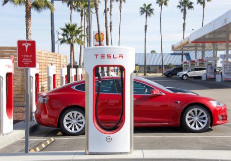 a red tesla charging station with palm trees in the background