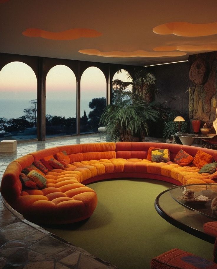 an orange couch sitting in the middle of a living room next to a large window