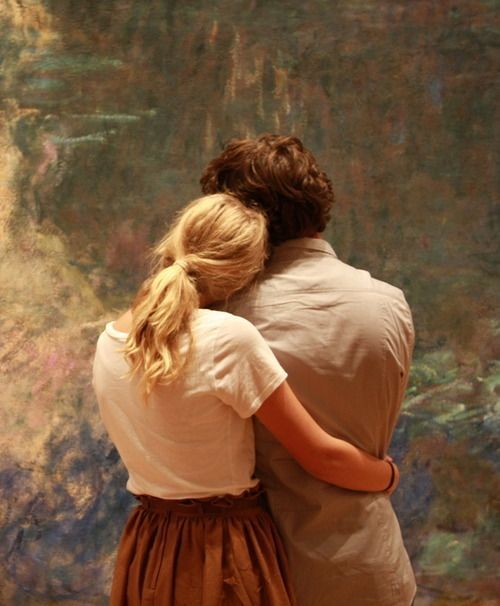 two people standing in front of a painting