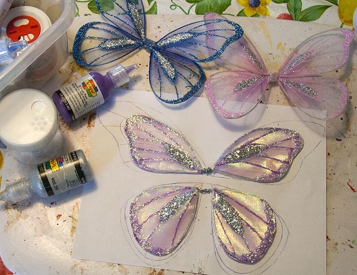 some crafting supplies are laying out on a table with butterfly wings and glues