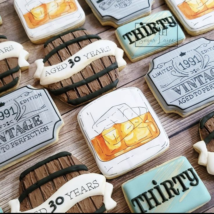 decorated cookies are displayed on a table with wine glasses and labels in the shape of whiskey bottles