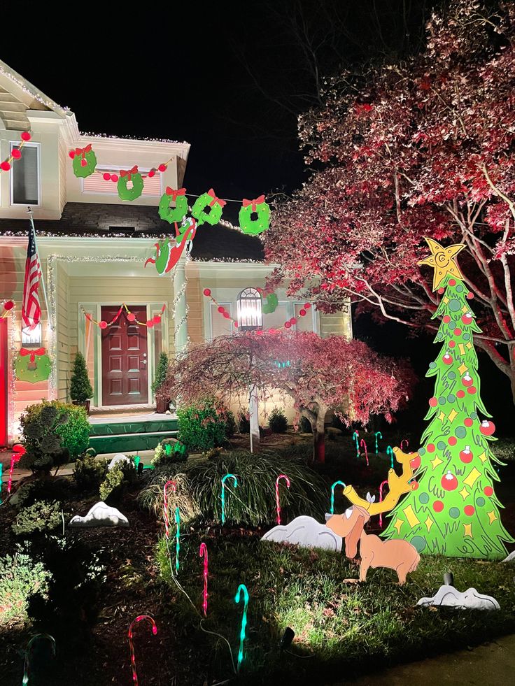 christmas lights decorate the front yard of a house with trees and candy canes on display