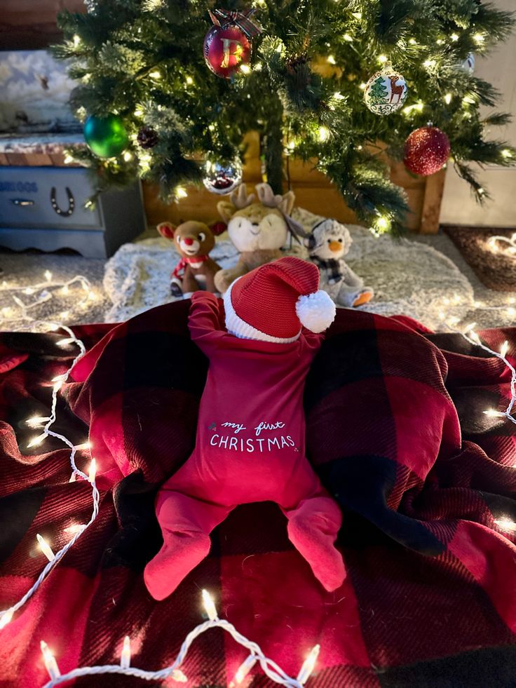 a christmas tree with lights in the background and a teddy bear laying on it's back