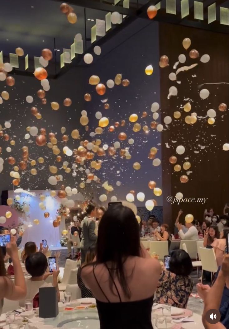 many people are sitting at tables with balloons in the air