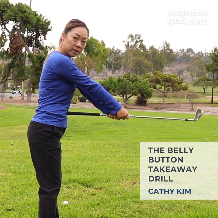 a woman hitting a golf ball with a tee on the grass in front of trees and a sign that says, the belly button takeaway drill kitty kim