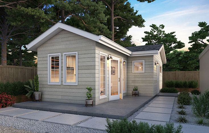 a small gray house sitting in the middle of a yard