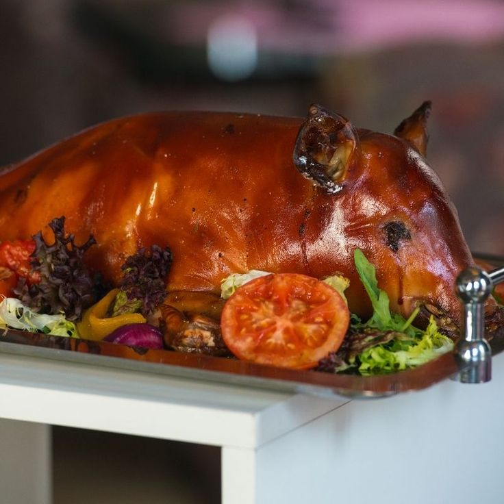 a large piece of meat on top of a table with tomatoes and lettuce