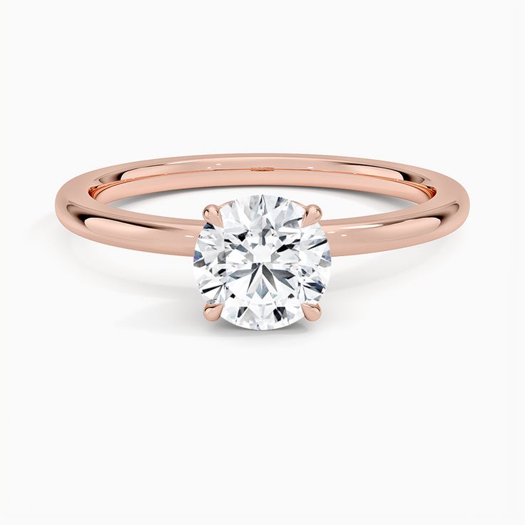 a rose gold engagement ring with a round cut diamond in the center, on a white background