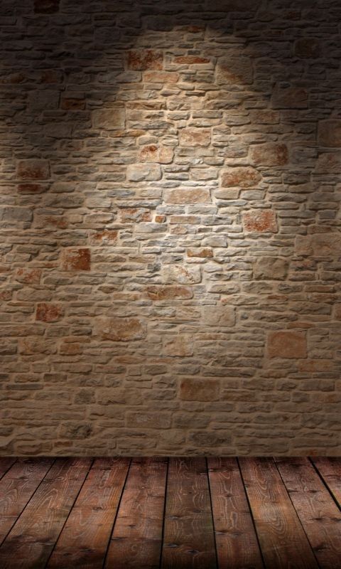 an empty room with a brick wall and wooden floor, lit by a spot light