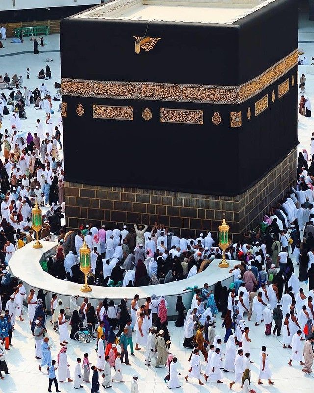 a large group of people walking around the ka'ba in the middle of a courtyard