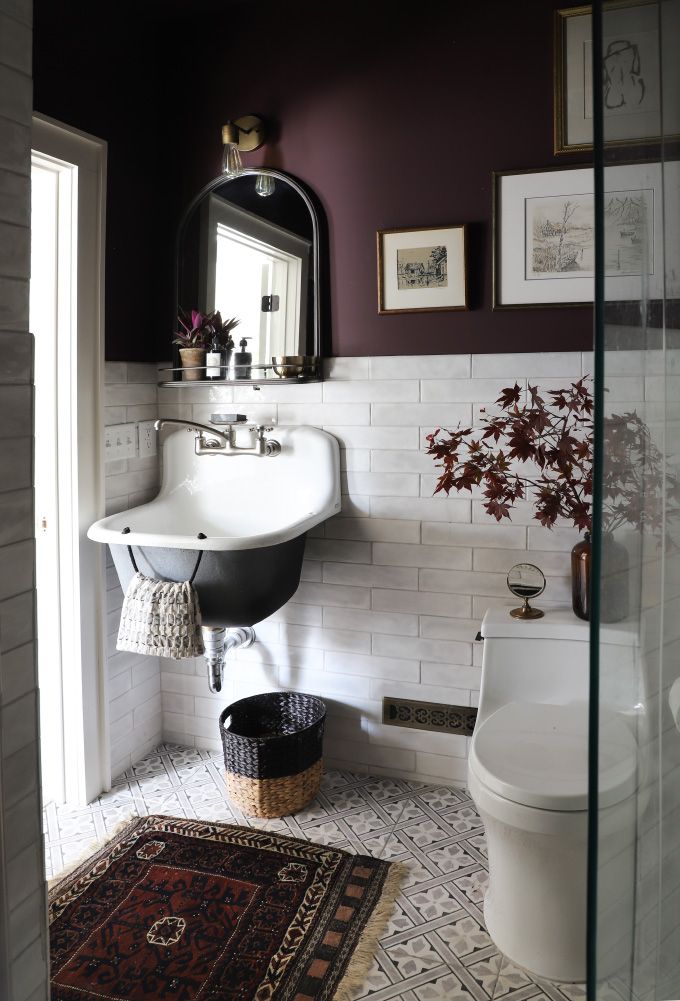 a white toilet sitting next to a sink in a bathroom under a mirror and a rug