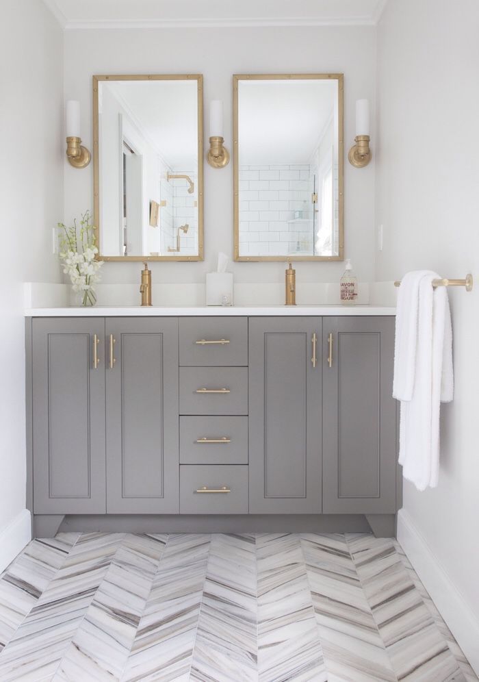 a bathroom with two mirrors and gray cabinets