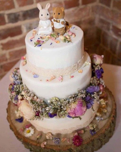 a wedding cake decorated with flowers and bunnies