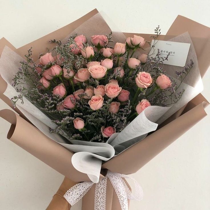 a bouquet of pink roses wrapped in brown paper