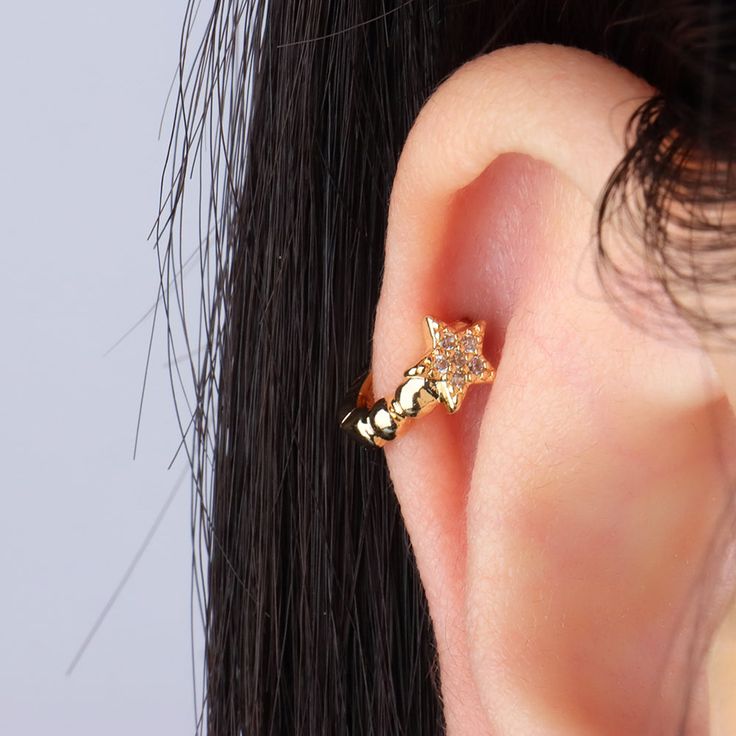 a close up of a person's ear wearing an earring with a star on it