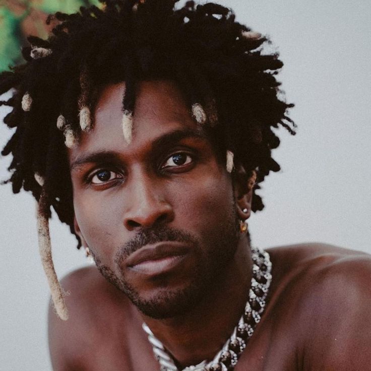 a close up of a person with dreadlocks on his head and necklace around his neck