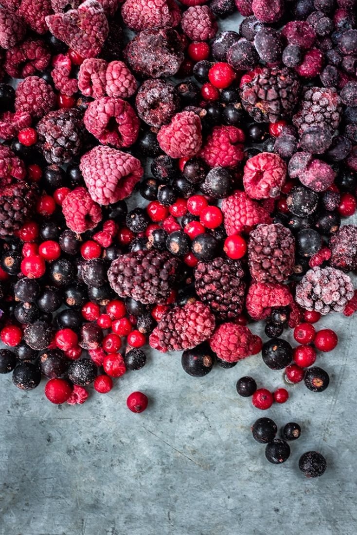 raspberries, blackberries and other berries are scattered on the concrete floor next to each other