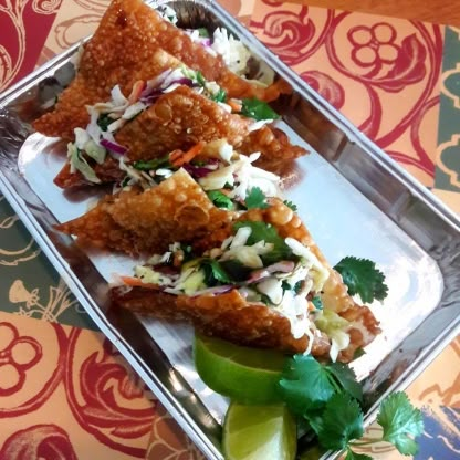 some food is on a metal tray with lime wedges and garnishes