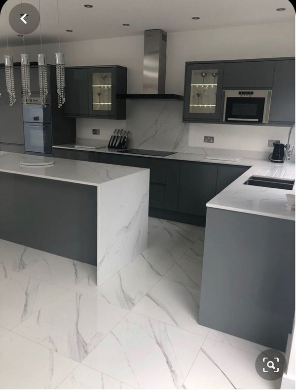 a large kitchen with marble counter tops and gray cabinets, along with white flooring