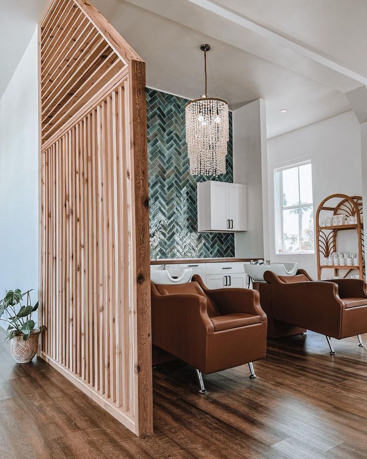 a living room filled with furniture and a chandelier hanging from the ceiling next to a kitchen