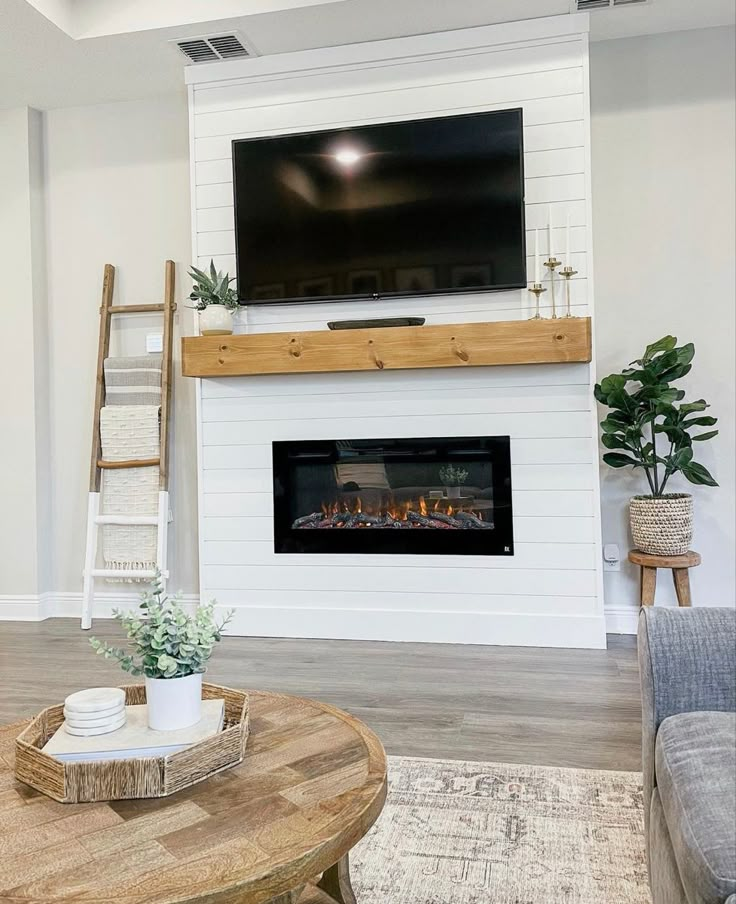 a living room with a fireplace and tv mounted on the wall above it is shown