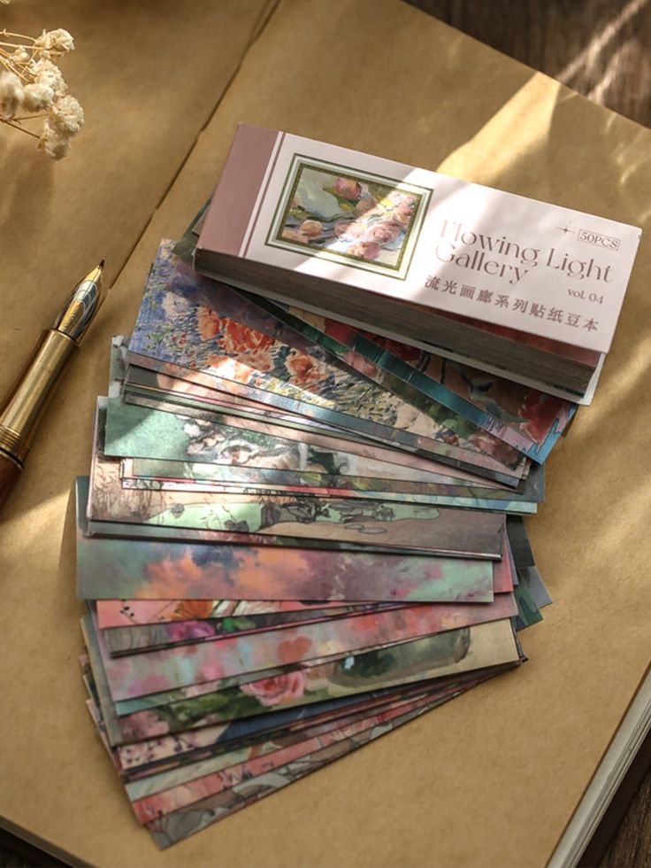 a pile of books sitting on top of a table next to a pen and paper