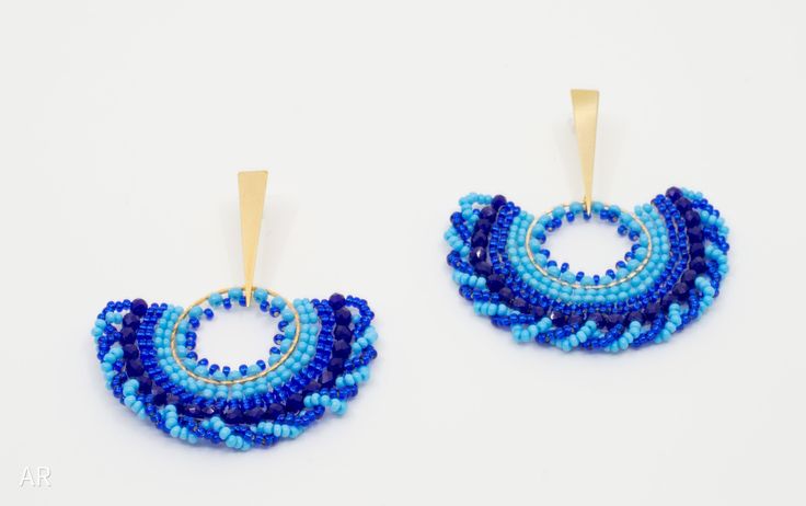 two pairs of blue beaded earrings with gold hoops on top of each other