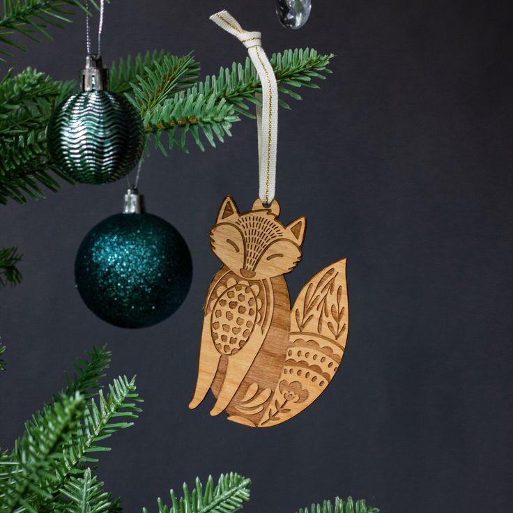 an owl ornament hanging from a christmas tree with ornaments around it on a black background