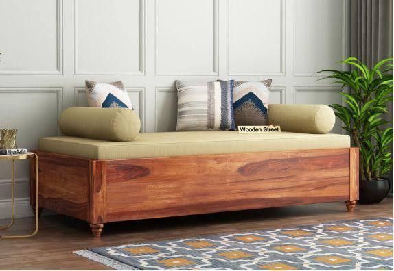 a wooden bench with pillows on it in front of a white wall and potted plant