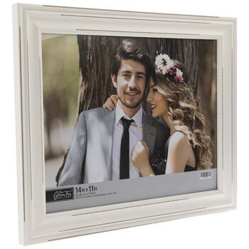 a white frame holds a photograph of a man and woman in front of a tree