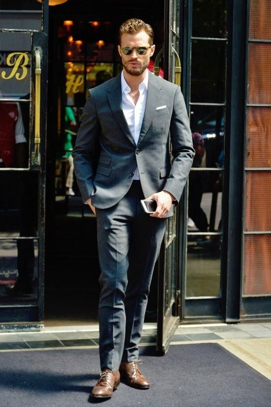 a man in a suit and sunglasses walking out of a building