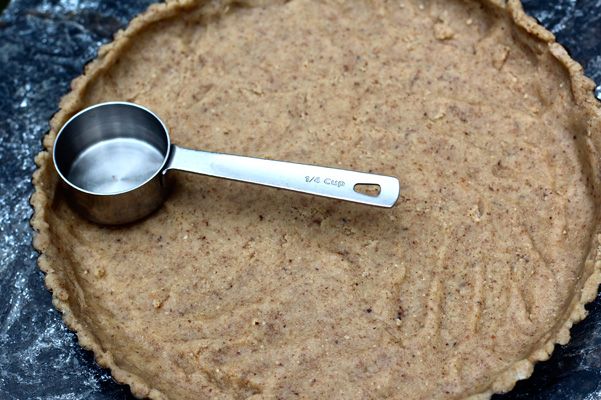 an uncooked pie crust with a measuring spoon