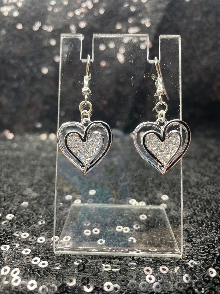 Black and silver heart earrings with rhinestones filling the center. Crystal Heart-shaped Earrings For Pierced Ears, Silver Heart Earrings With Rhinestones For Gift, Heart-shaped Rhinestone Earrings For Anniversary, Silver Open Heart Earrings For Party, Heart-shaped Metal Crystal Earrings, Anniversary Heart Earrings With Rhinestones, Silver Heart Earrings With Rhinestones For Party, Heart-shaped Rhinestone Earrings For Gift, Silver Heart Crystal Earrings For Pierced Ears